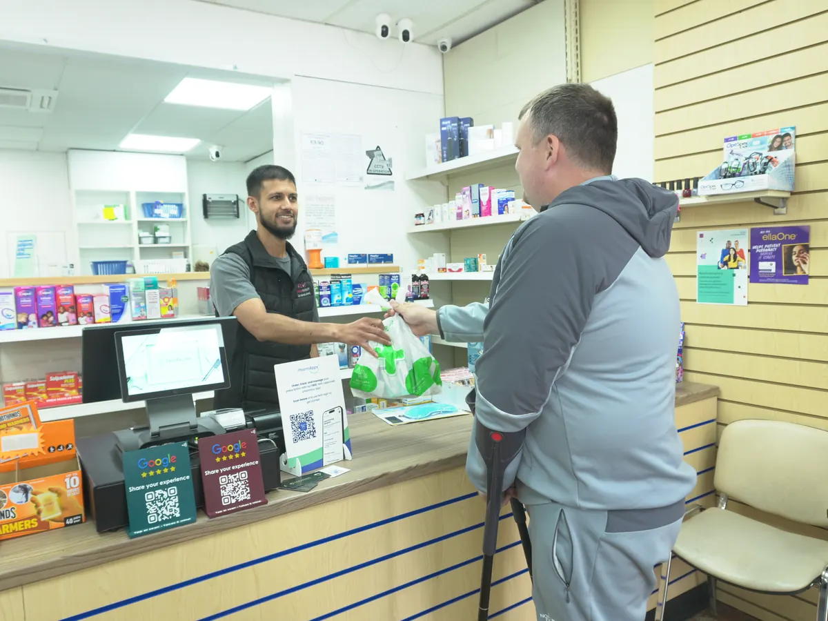 Our pharmacist handing a customer their prescription at the Glen Parva counter